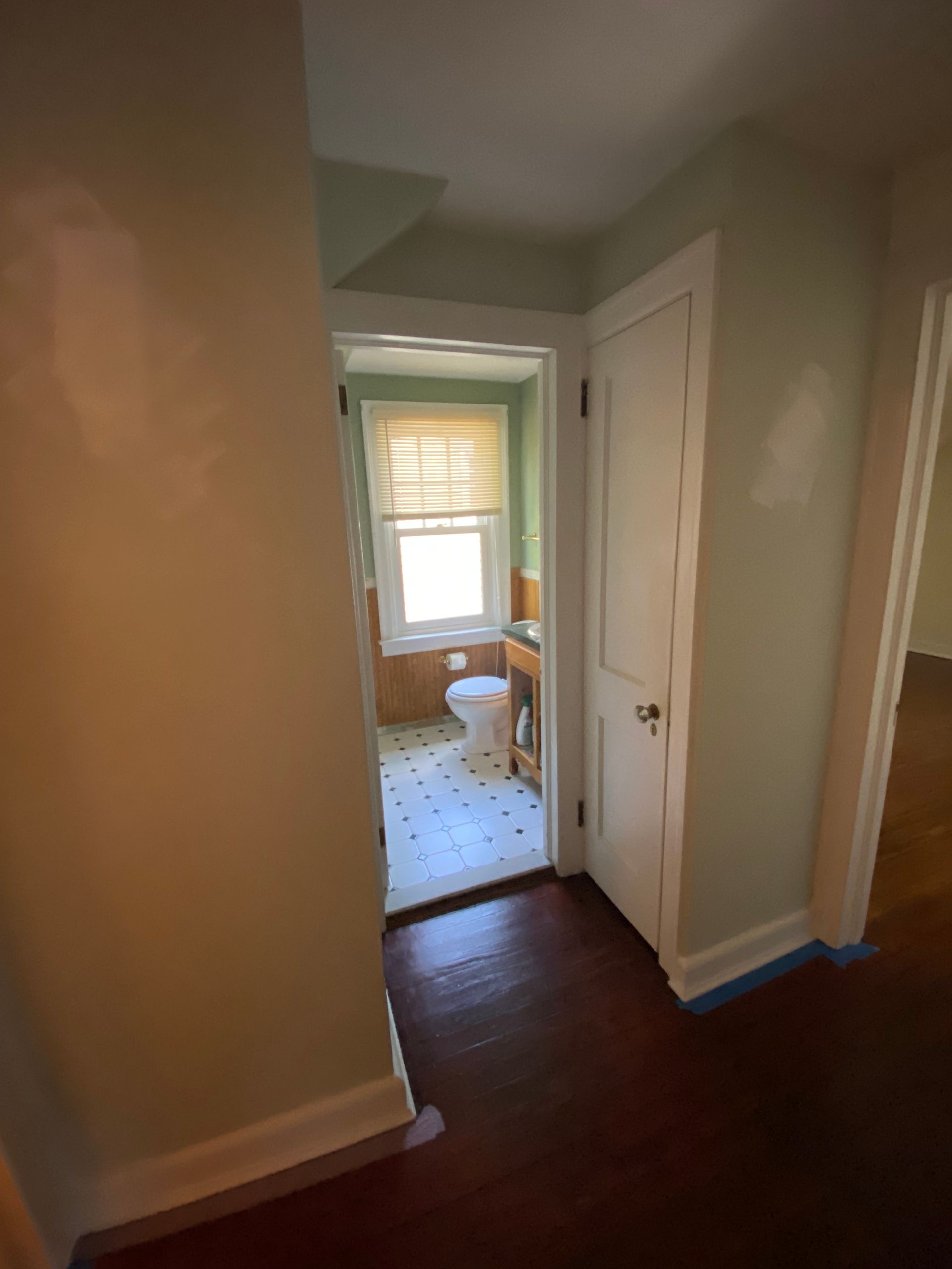 A hallway leading to a bathroom with a toilet and sink.