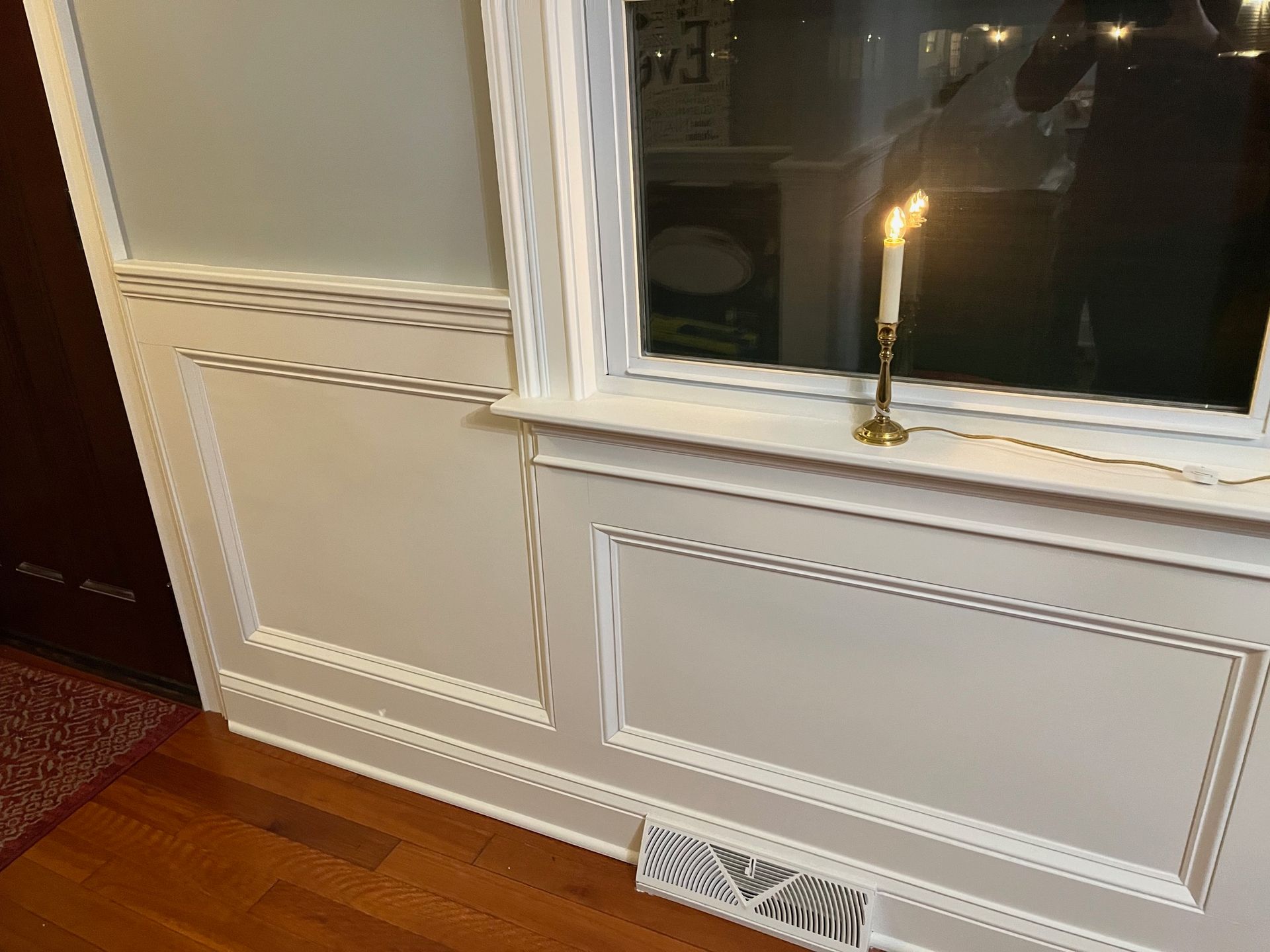 A candle is lit in front of a window in a room.