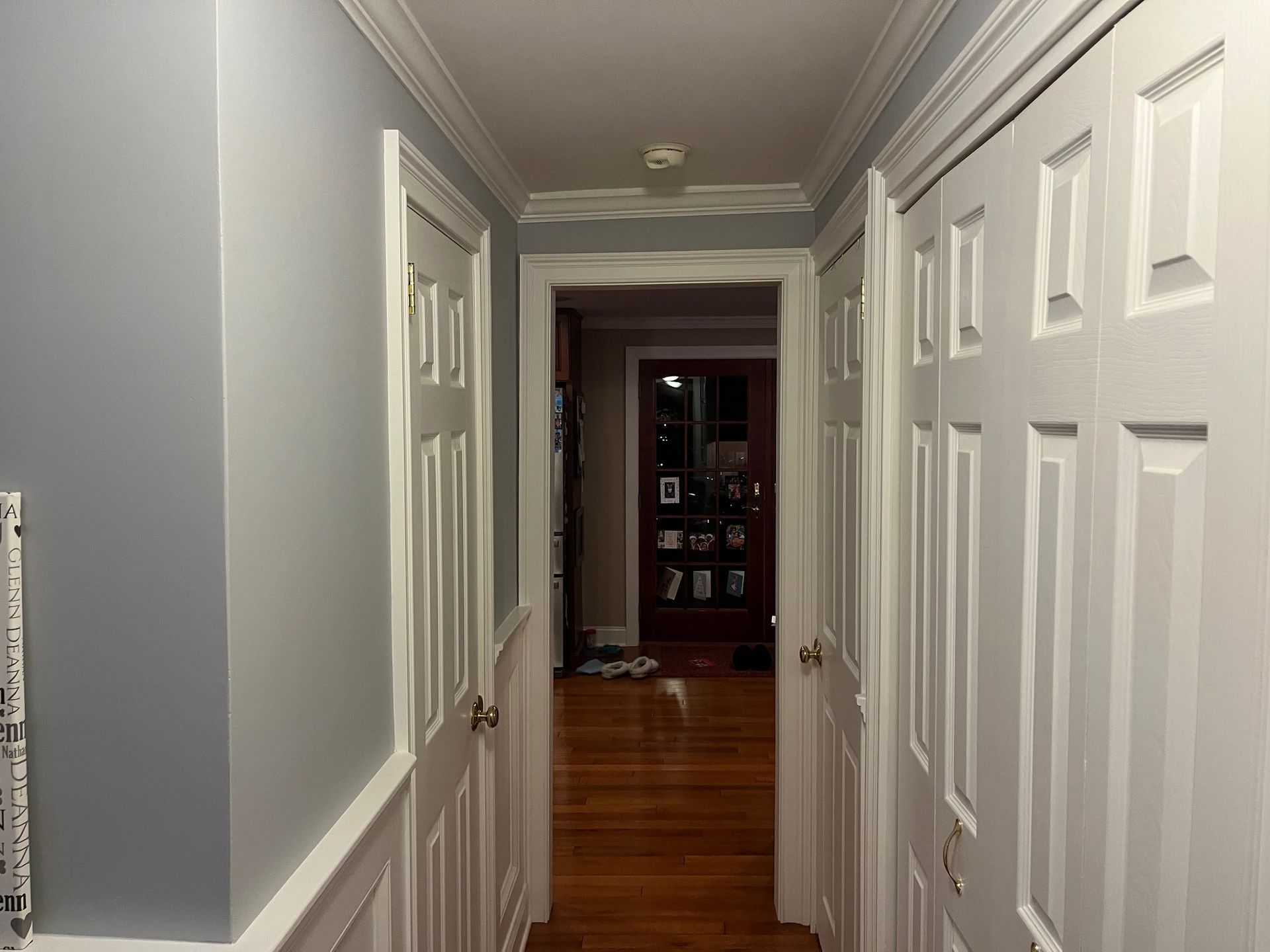 A hallway with a lot of white doors and a wooden floor.