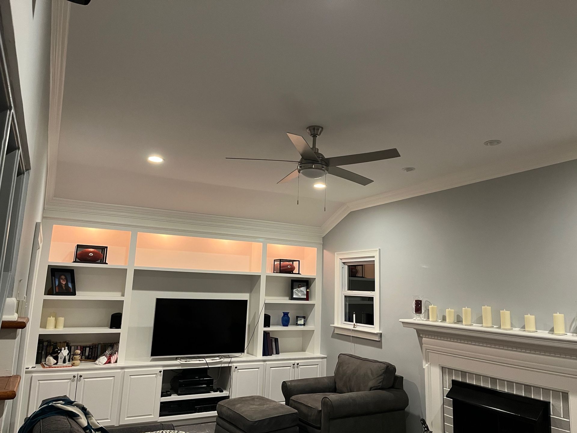 A living room with a fireplace and a ceiling fan