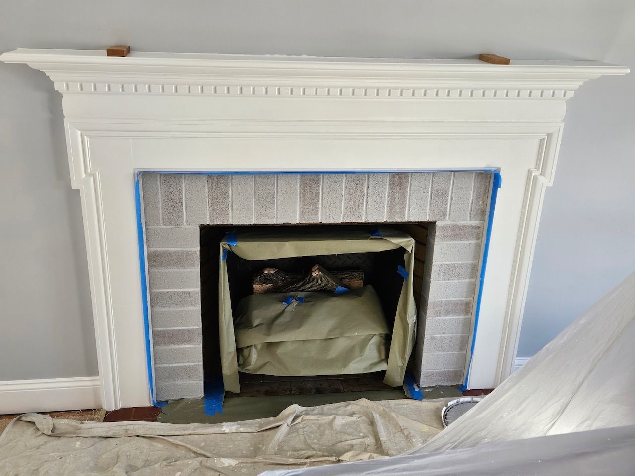 A fireplace is being painted in a living room