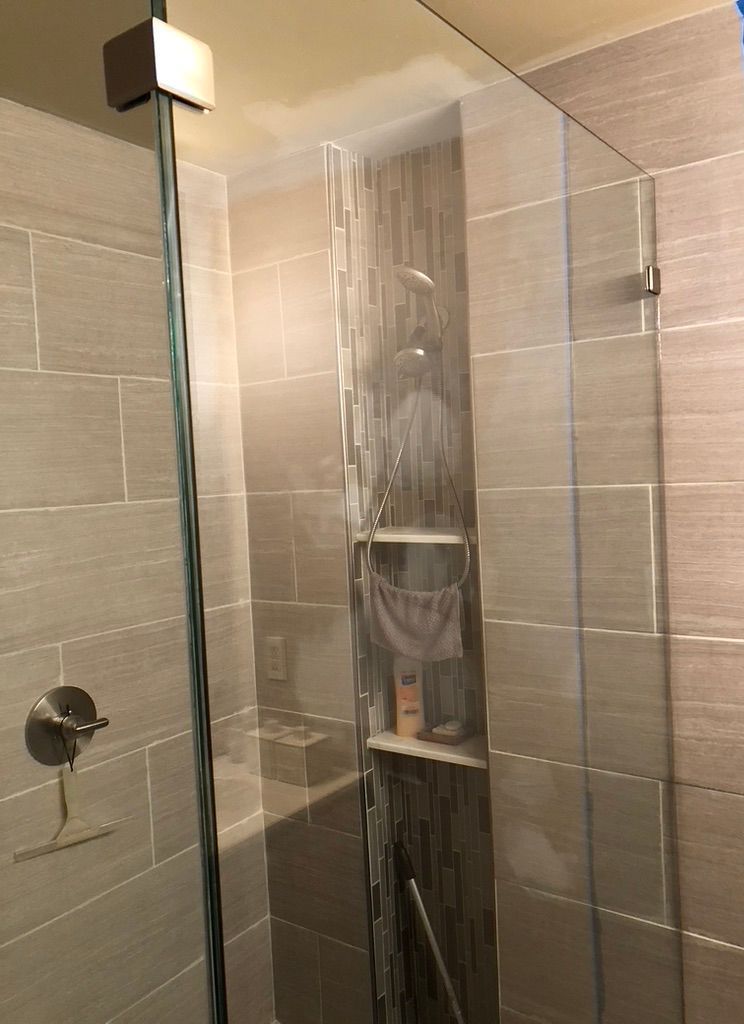 A bathroom with a walk in shower with a glass door.