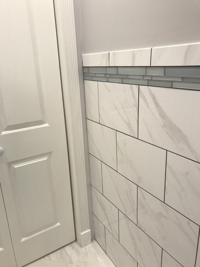 A bathroom with white tiles on the wall and a door.