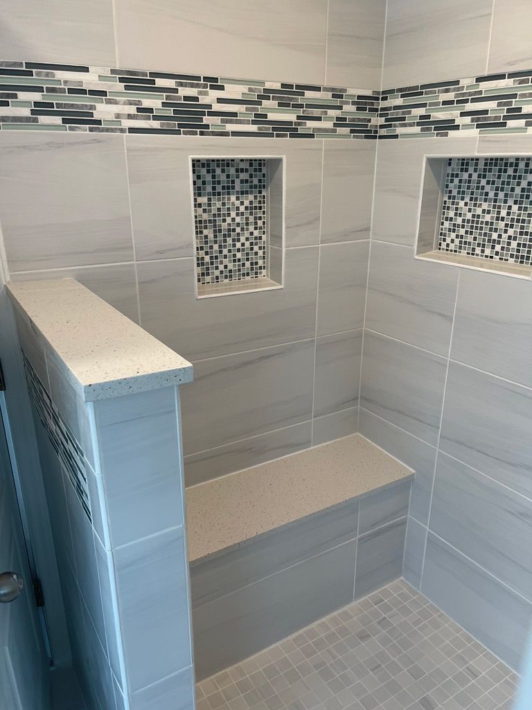 A shower with a bench and two niches on the wall.