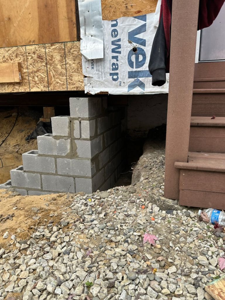 A brick wall is being built under a house.