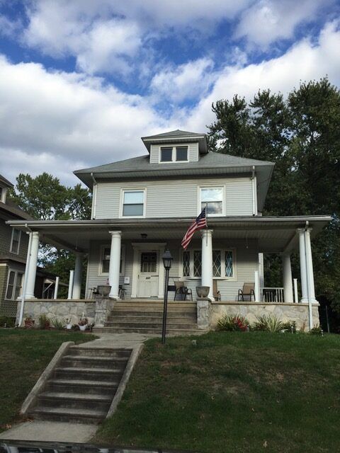 A large white house with a porch and stairs