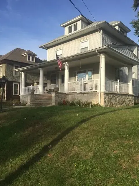 A large house with a large porch and a flag on it
