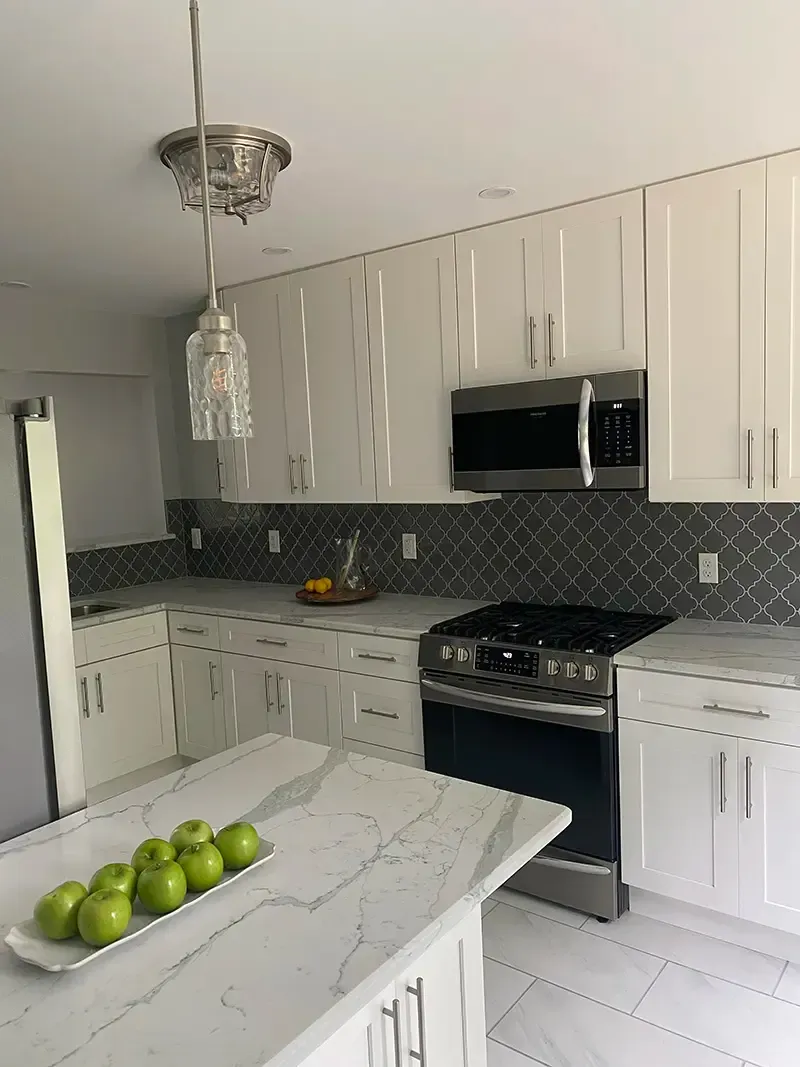 A kitchen with white cabinets , stainless steel appliances , a stove and a microwave.