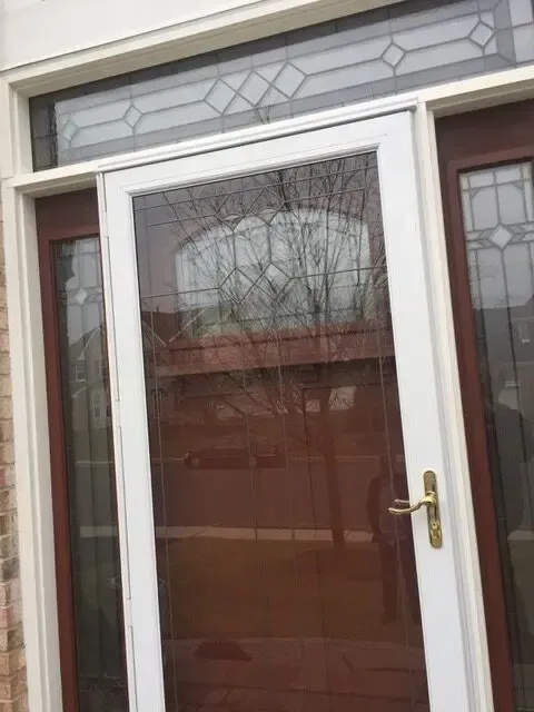 A white door with a brown door and a stained glass window.