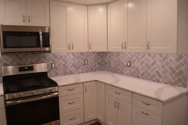 A kitchen with white cabinets , stainless steel appliances , a stove and a microwave.