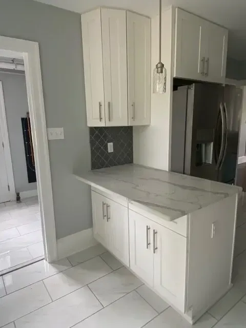 A kitchen with white cabinets and a marble counter top.