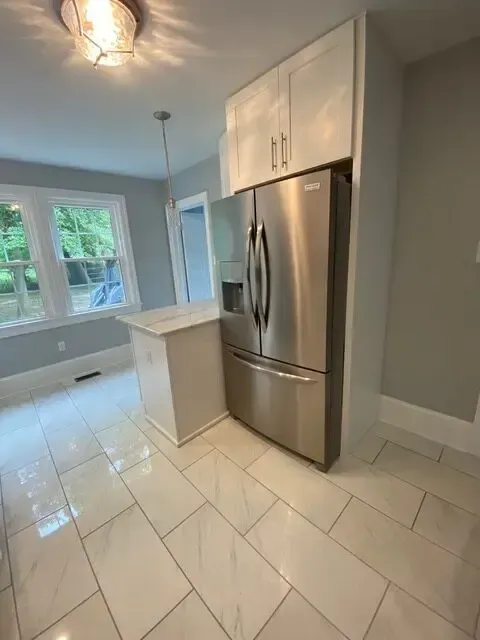 A kitchen with a stainless steel refrigerator and a white tile floor.