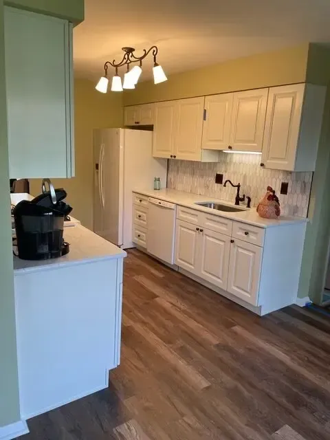 A kitchen with white cabinets and hardwood floors