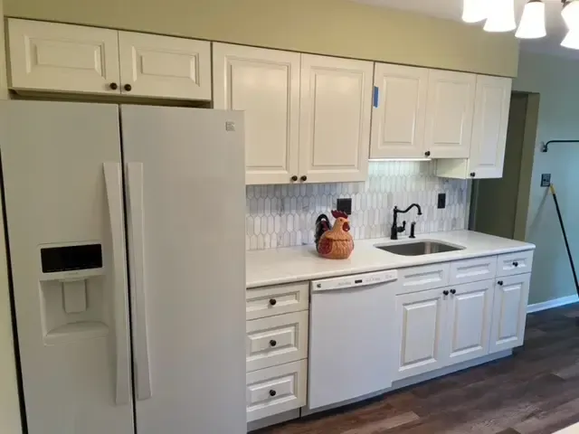 A kitchen with white cabinets and a white refrigerator