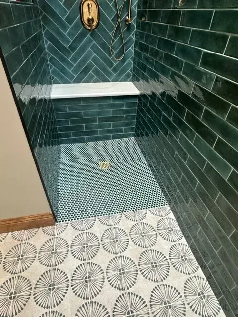A bathroom with green tiles and a walk in shower.
