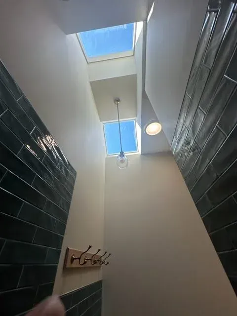 A person is looking up at a skylight in a bathroom.