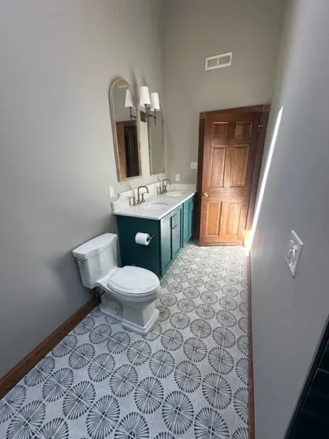 A bathroom with a toilet , sink and mirror.