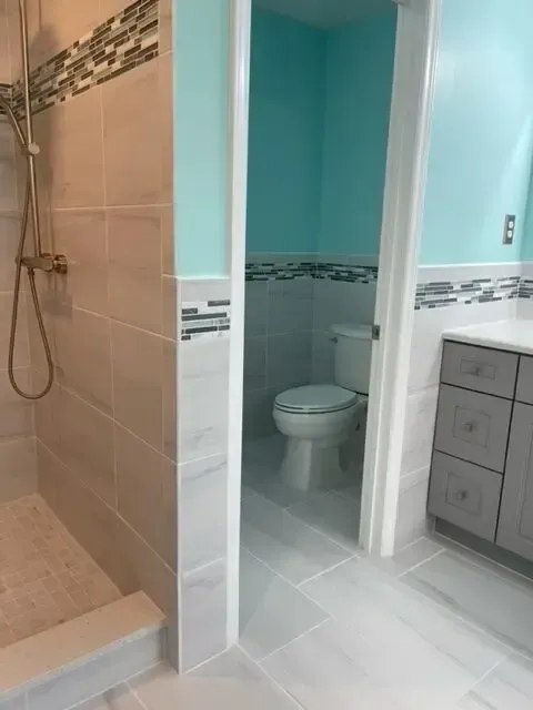 A bathroom with a toilet , shower and sink.