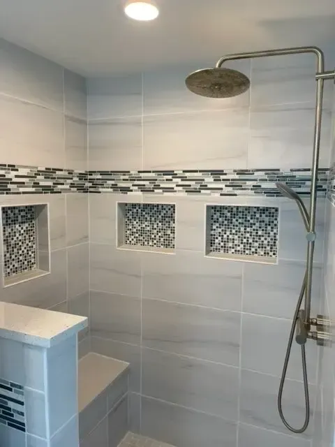 There is a shower with a bench and a shower head.