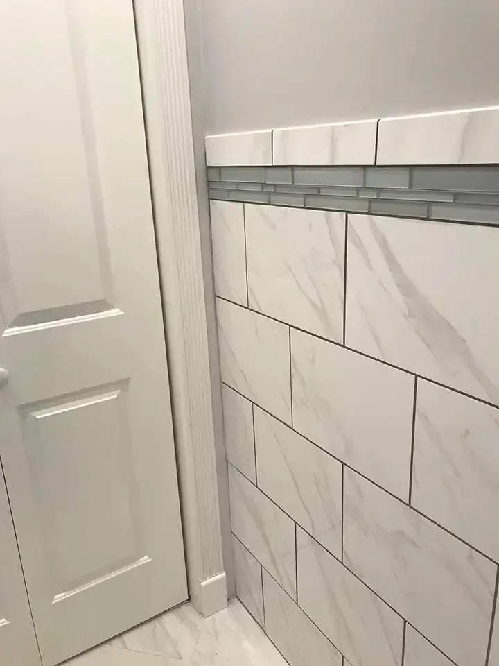 A bathroom with white tiles on the wall and a door.