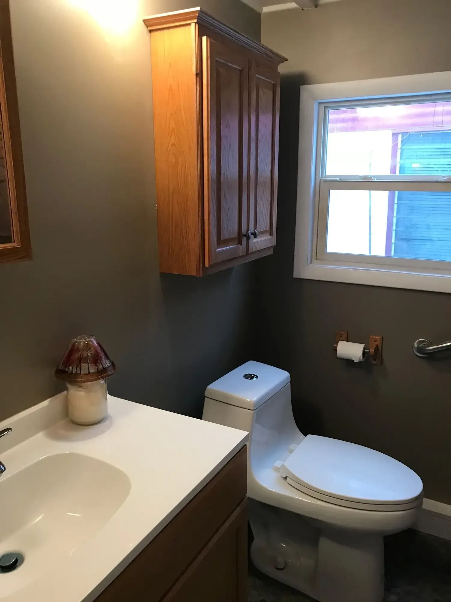 A bathroom with a toilet a sink and a window