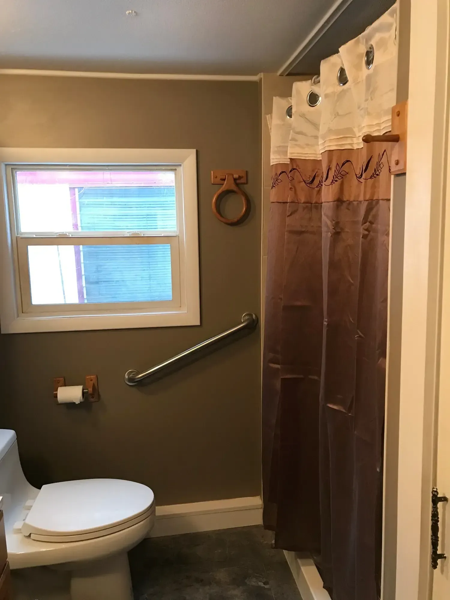 A bathroom with a toilet , shower curtain and window.