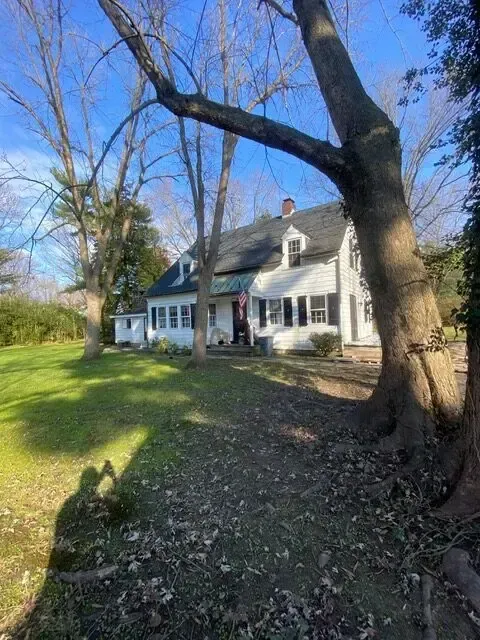 A white house with a black roof is surrounded by trees and grass.