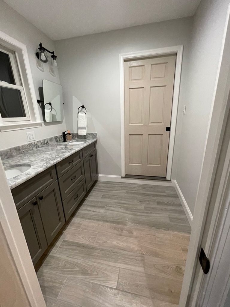 A bathroom with two sinks , a mirror , and a door.