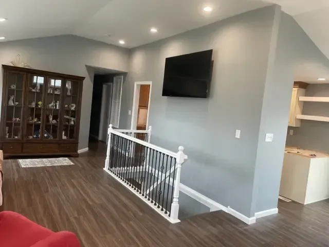 A living room with a staircase and a flat screen tv on the wall