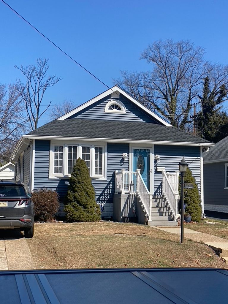 A blue and white house with a car parked in front of it.