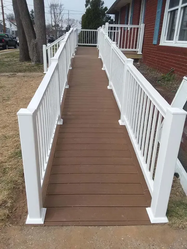 A ramp with a white railing leading to a house