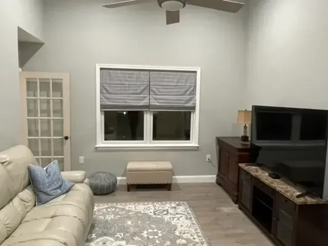 A living room with a couch , television , and a ceiling fan.