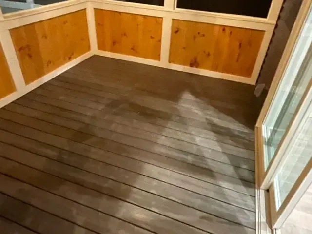 A screened in porch with wooden walls and a wooden floor