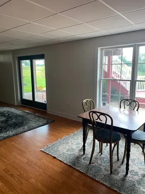 A dining room with a table and chairs and a rug.