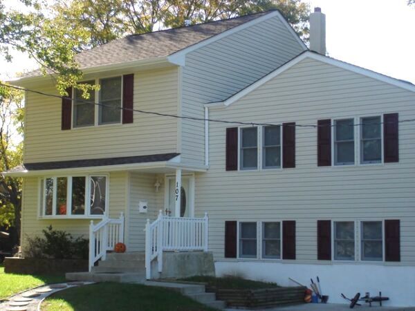 A white house with brown shutters and a white porch