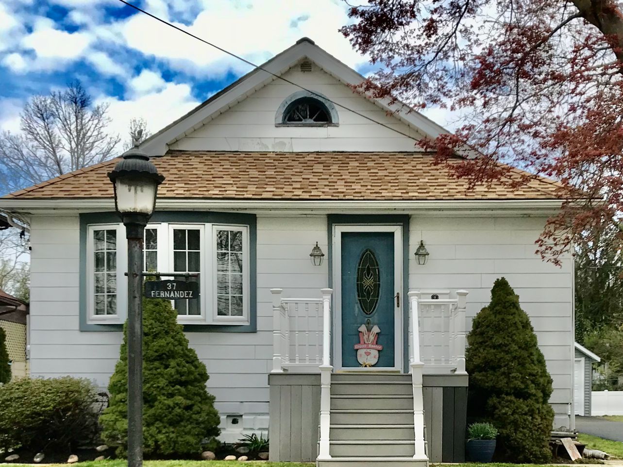 A white house with a brown roof and a blue door