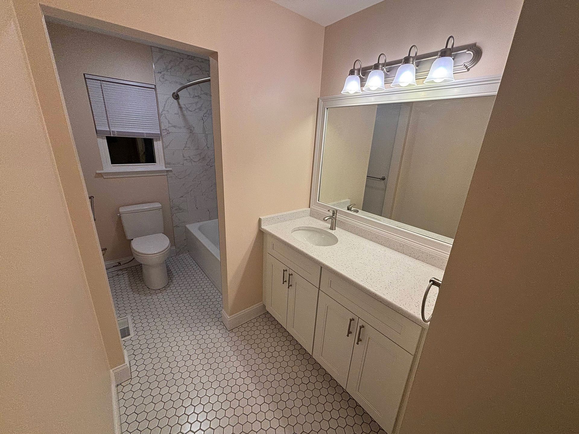 A bathroom with a toilet , sink , and mirror.