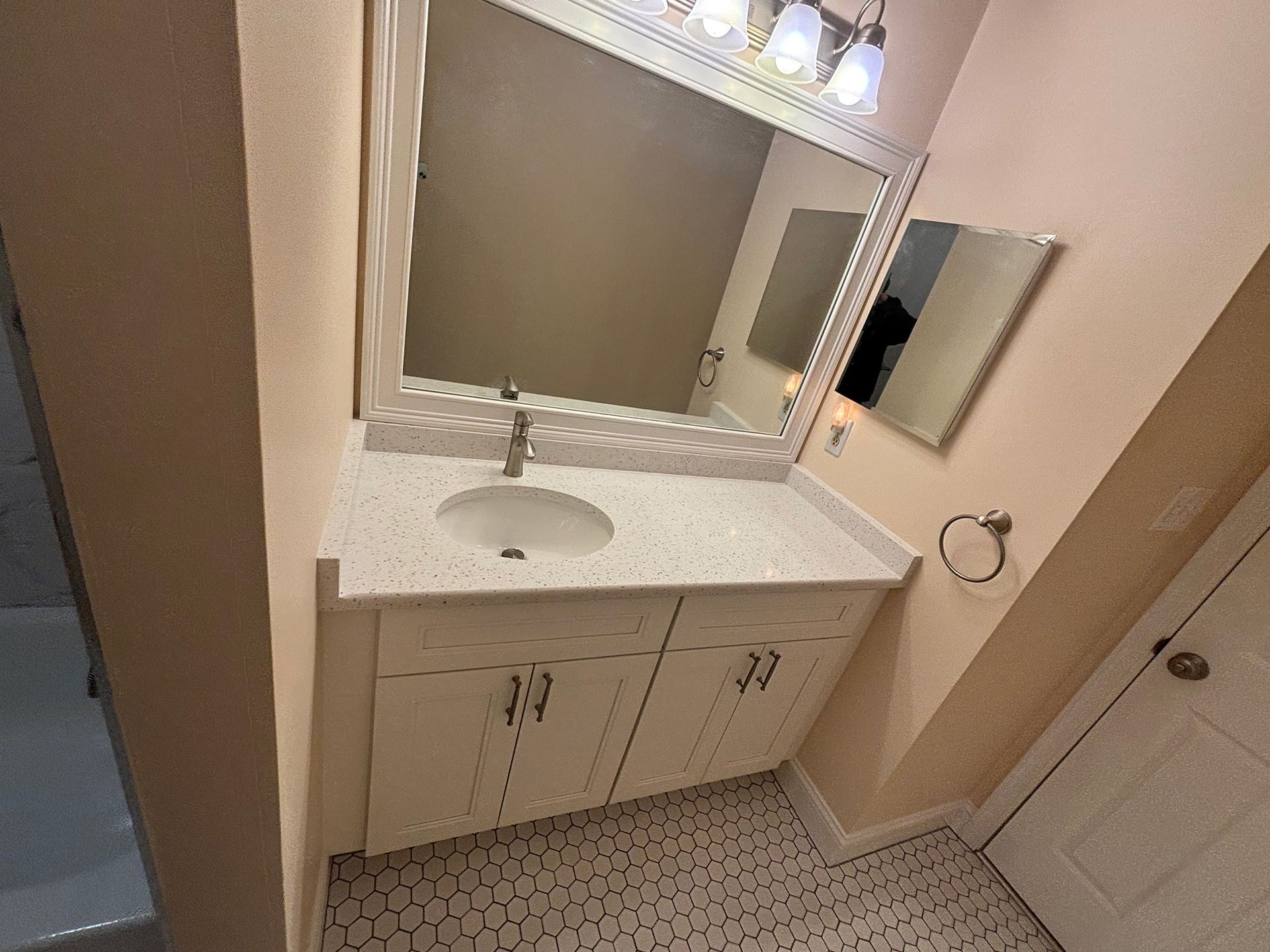 A bathroom with a sink , mirror and cabinets.