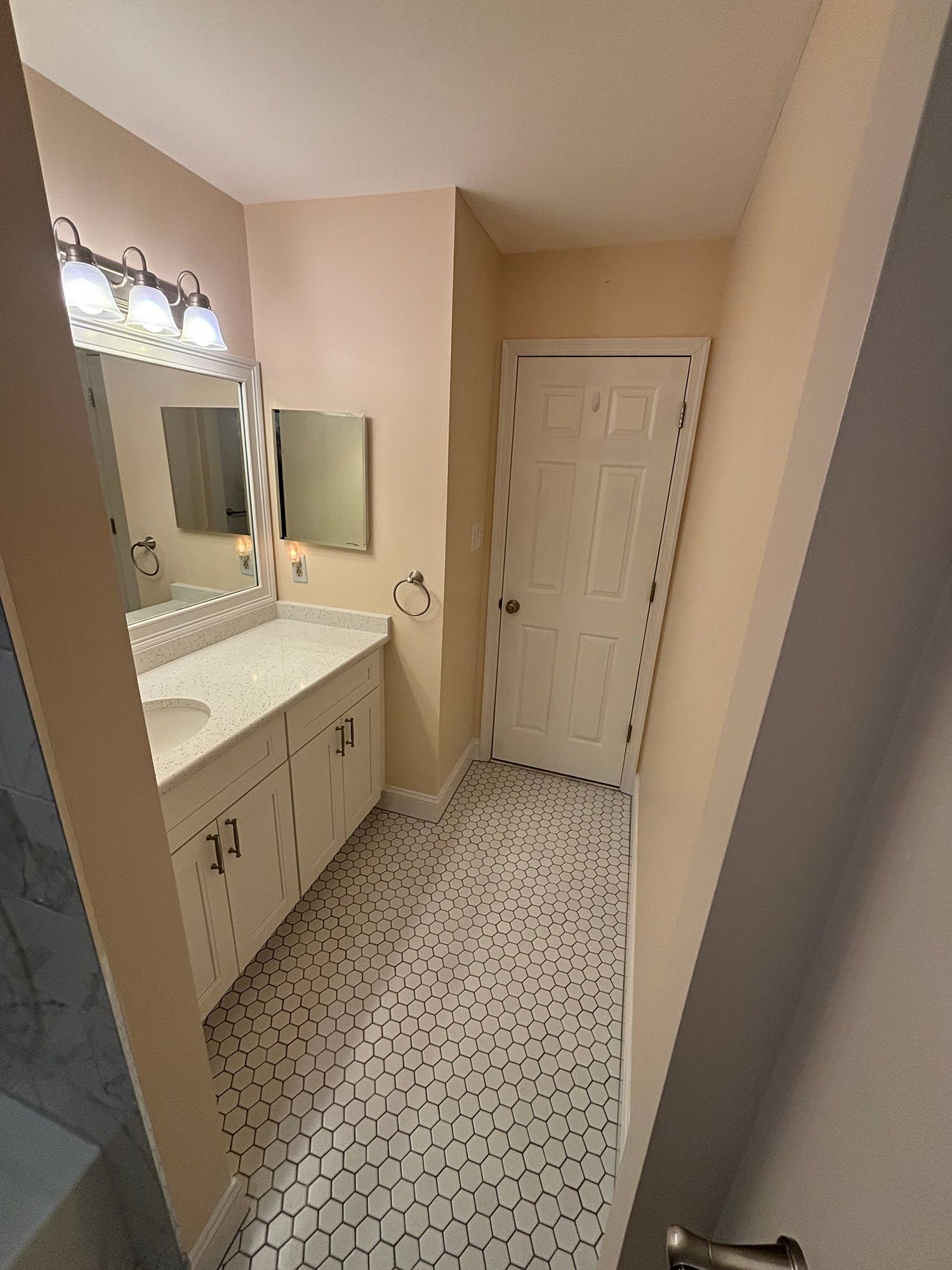 A bathroom with a sink , mirror , and hexagonal tile floor.