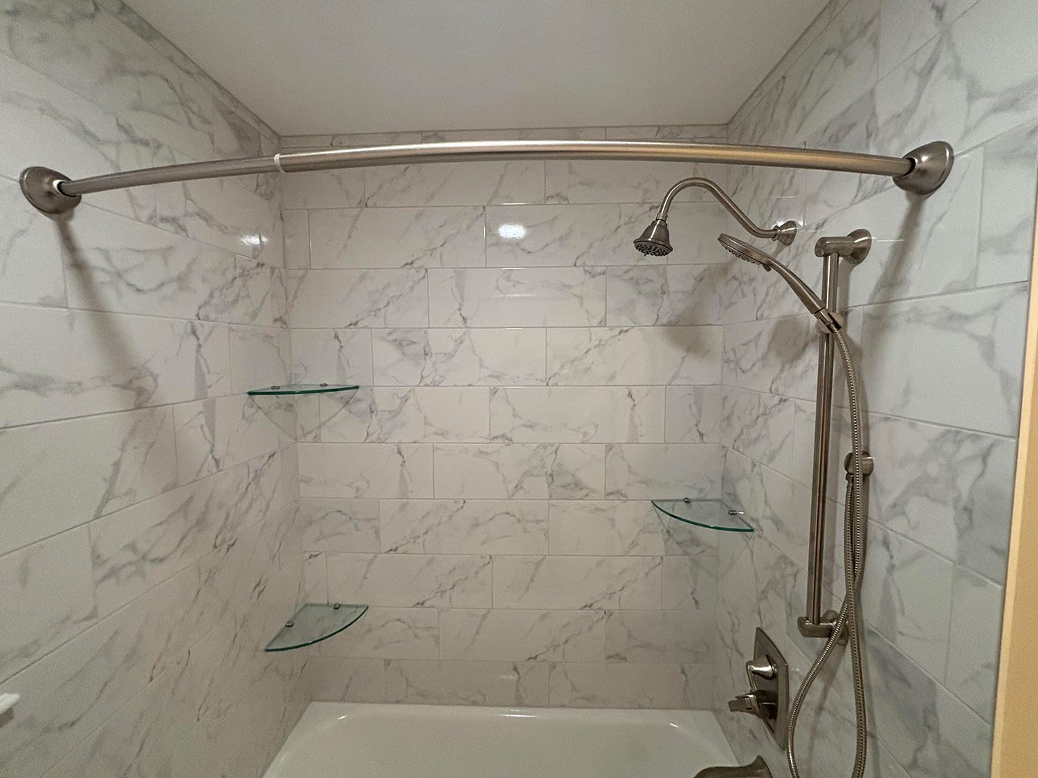 A bathroom with marble walls and a bathtub with a shower head.