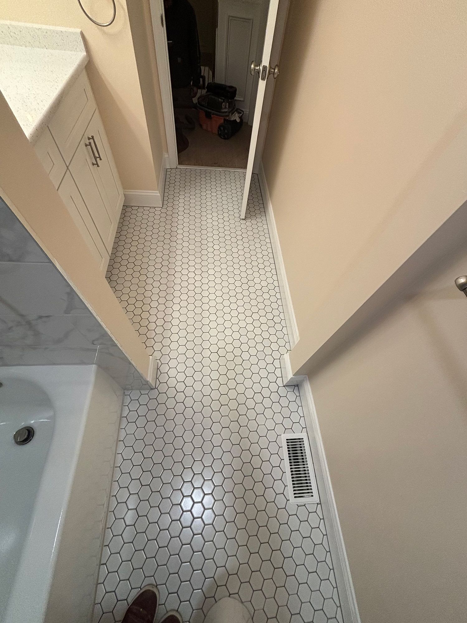 A bathroom with white tile floors and a bathtub.