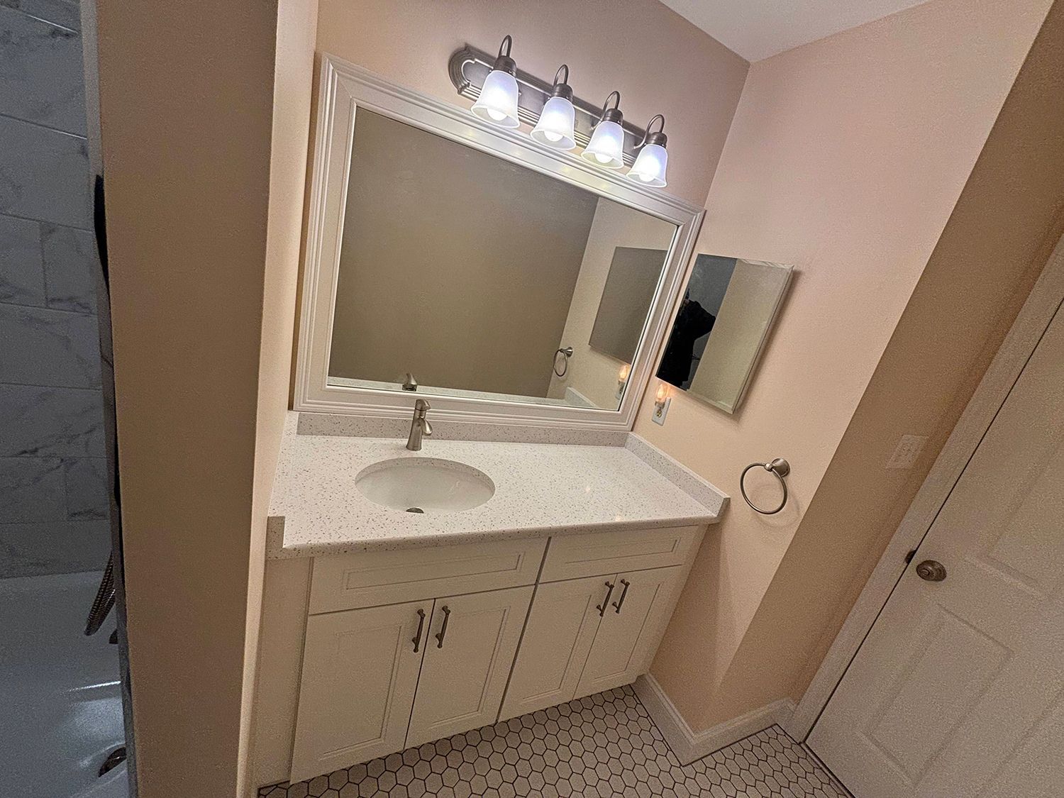 A bathroom with a sink , mirror and light fixture.