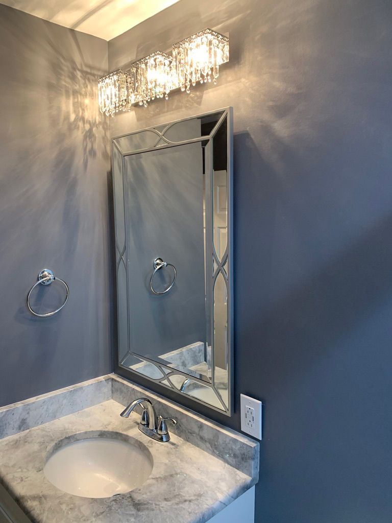 A bathroom with a sink , mirror and light fixture.
