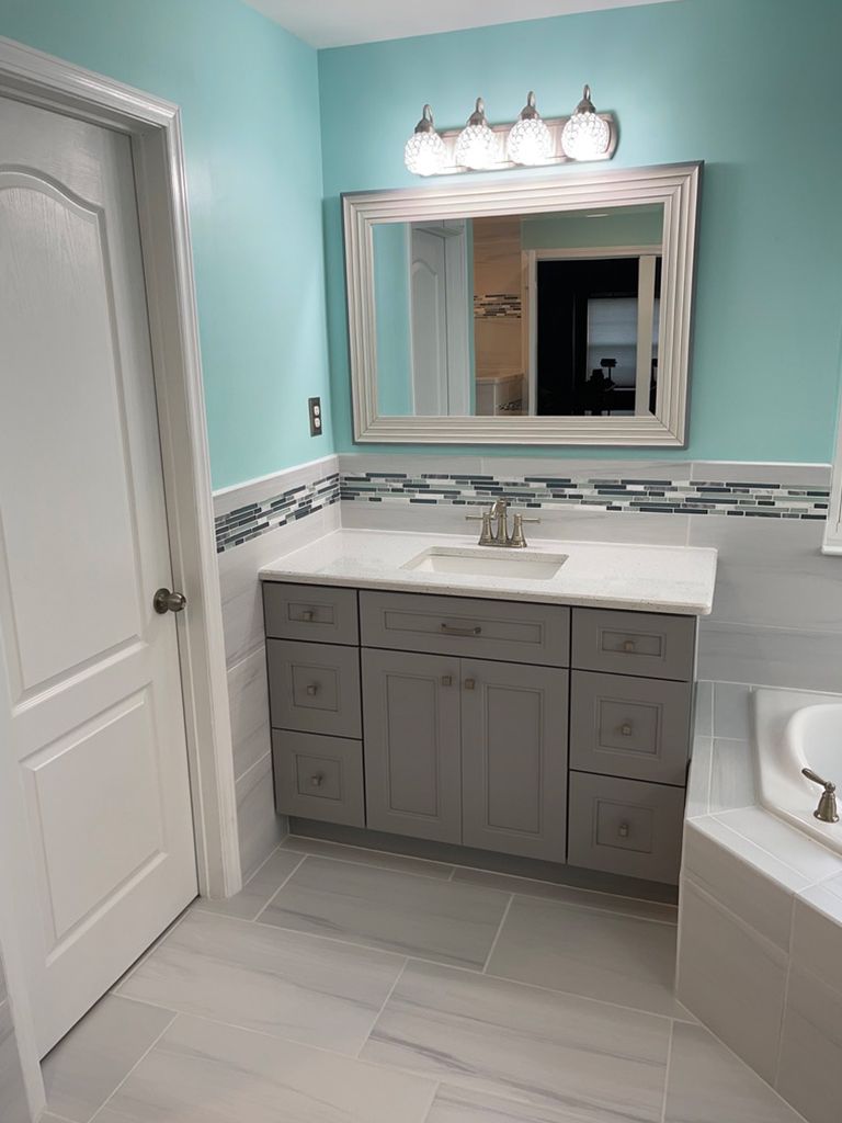 A bathroom with a sink , mirror , and bathtub.