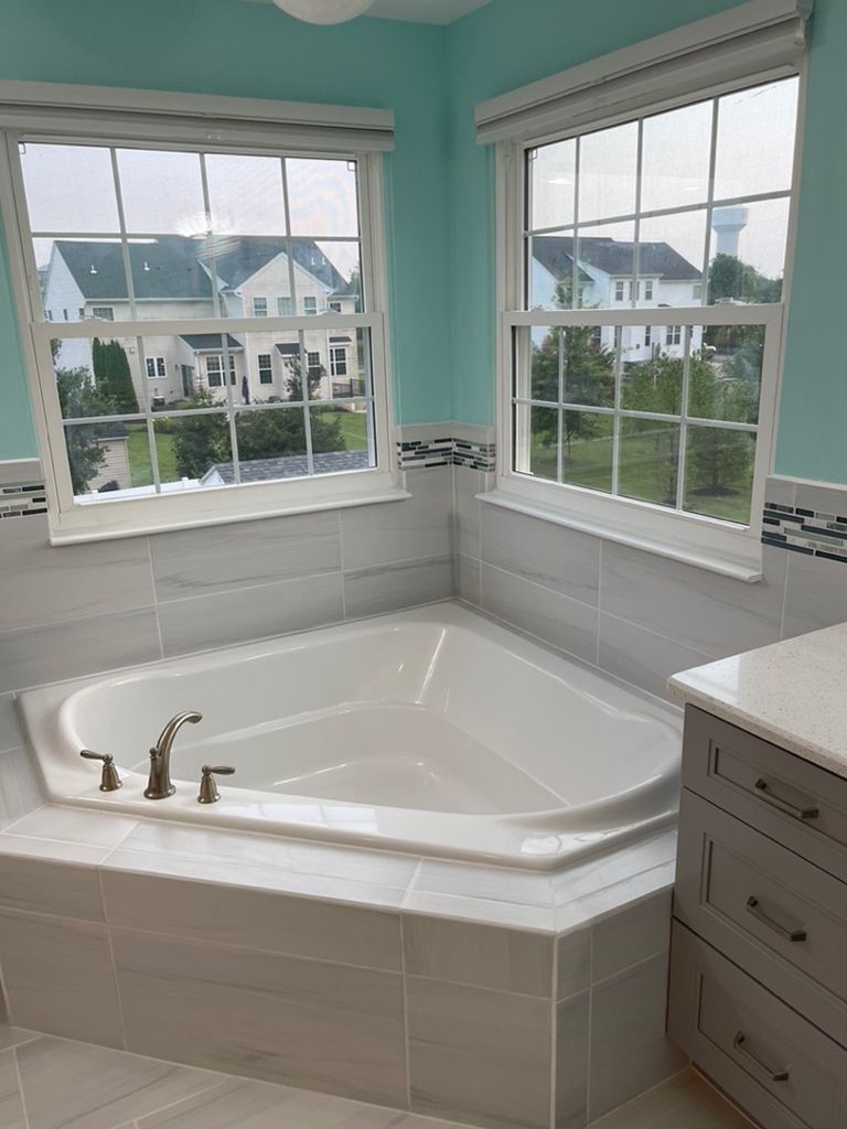 A bathroom with a jacuzzi tub and two windows.