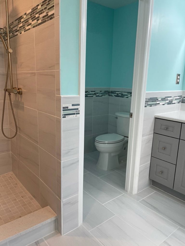 A bathroom with a toilet , shower and sink.