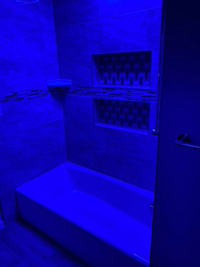 A bathtub is lit up with blue light in a bathroom.