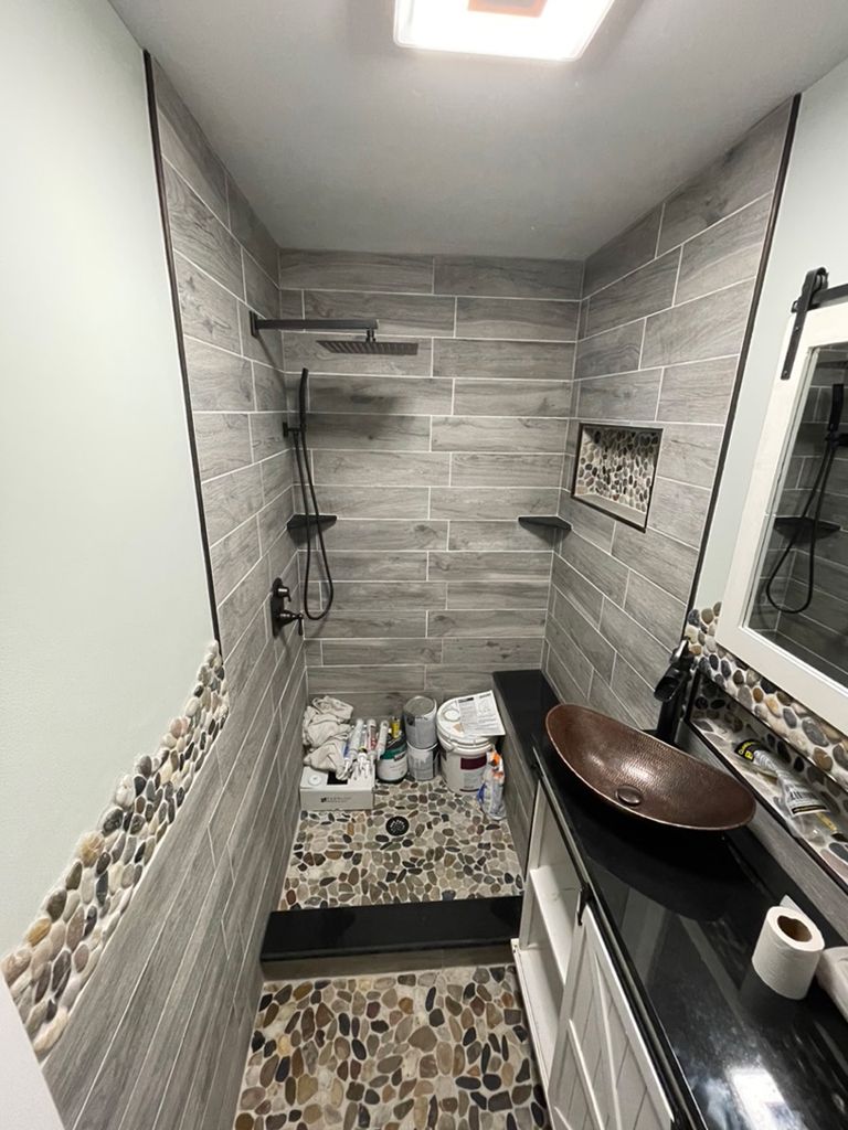 A bathroom with a sink , mirror and shower.