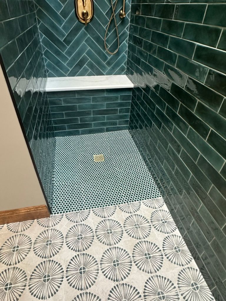 A bathroom with green tiles and a walk in shower.