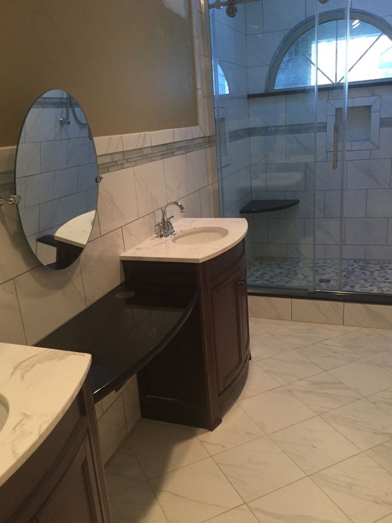 A bathroom with a sink , mirror and walk in shower.